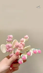 Détail de la pince à cheveux crème avec motifs de pêche rose, nœud et petit ours
