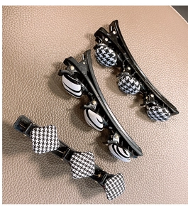 Détail de trois barrettes à motif pied-de-poule noir et blanc avec clips pour tresses