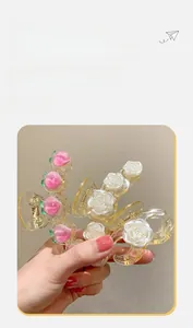 Détail de pinces à cheveux en résine pêche et camélia perlé avec ressort en métal