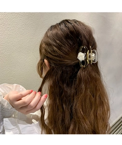 Détail d'une pince à cheveux jaune avec des fleurs 3D blanches dans une coiffure chic