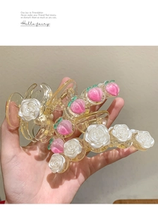 Vue détaillée de grandes pinces à cheveux en acrylique avec roses et pêches roses