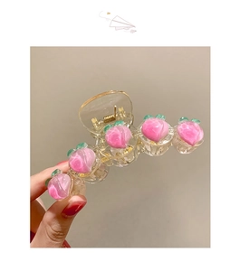 Détail de la pince à cheveux pêche avec cinq pêches en résine rose et feuilles vertes