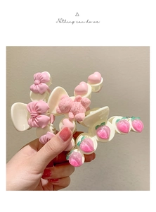 Gros plan de pinces à cheveux rose avec ours et fraise tenues à la main en détail