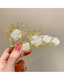 Détail de pinces à cheveux en résine pêche ornées d'élégantes roses blanches en relief