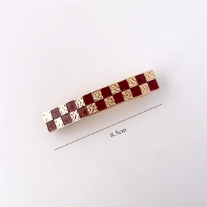 Detail showing the 8.5cm red and gold checkered pattern hair clip with hammered texture