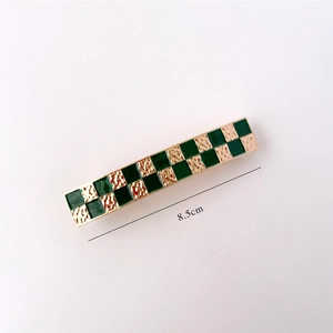 Detail view of 8.5cm checkered hair clip with gold hammered texture and green enamel finish