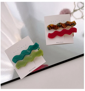 Makroaufnahme von vier bunten gewellten Haarspangen aus Harz mit glänzendem Finish