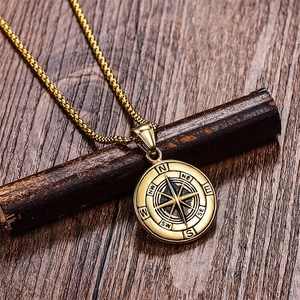 Macro shot of gold compass pendant with compass rose on dark wood branch background