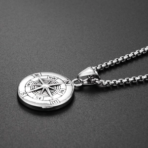 Close-up of silver compass pendant with intricate North Star engraving on box chain