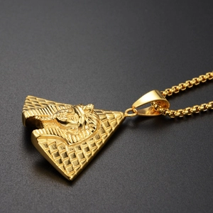 Macro shot of Egyptian pharaoh and pyramid pendant on golden metal box chain