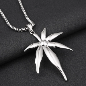 Macro shot of polished silver maple leaf pendant with fine bead chain on gray fabric