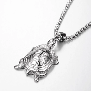 Collar con colgante de tortuga de plata pulida y cadena de caja sobre fondo gris claro