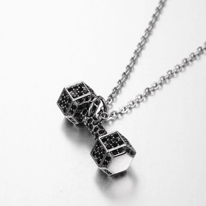 Detailed view of silver dumbbell pendant with black zircon inlays on a metal surface
