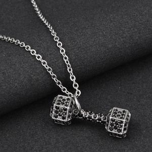 Macro shot of silver dumbbell pendant with black rhinestones on a fine link chain