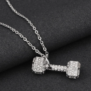 Macro view of silver dumbbell pendant with sparkling crystals on a textured chain