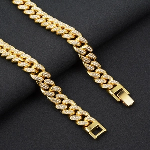 Detail shot of golden hip hop Cuban link chain with full zircon paving on black surface