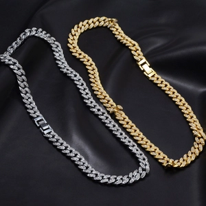 Macro detail of gold and silver iced-out cuban link necklaces on black satin background