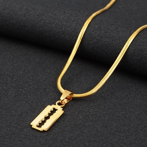 Dettaglio macro del ciondolo a lama di rasoio dorata su un'elegante collana a serpente