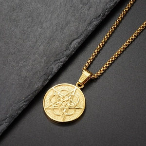 Detailaufnahme des goldenen Pentagramm-Anhängers an einer Box-Kette auf grauem Stein