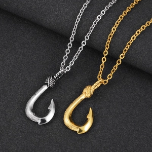 Macro detail of silver and gold fish hook pendants with intricate engraved patterns