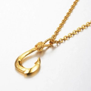 Macro shot of gold fish hook pendant with Hawaiian carvings and rollo chain necklace