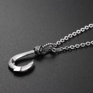 Macro shot of vintage silver fish hook pendant with ethnic engravings on steel chain