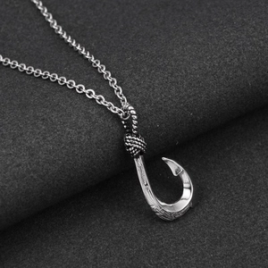 Detailed close-up of a silver fish hook pendant with vintage engravings and S925 stamp