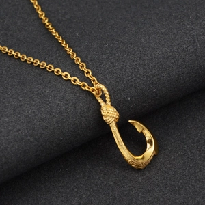 Macro shot of golden fish hook pendant with tribal carvings and knotted bail detail