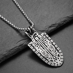 Detail of Viking shield pendant with intricate Celtic knots on textured stone backdrop