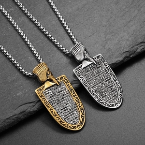 Macro shot of Egyptian shield pendants in gold and silver with black crystal pavé
