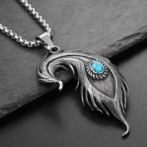 Détail du pendentif plume en acier vintage avec pierre turquoise sur surface sombre