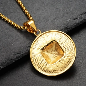 Macro d'un pendentif disque pyramide doré en acier avec texture radiale sur pierre