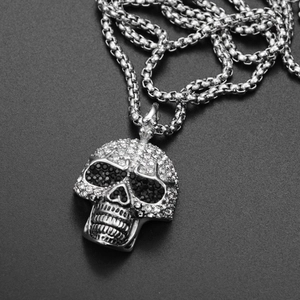 Makroansicht des silbernen Totenkopfanhängers mit funkelnden Diamanten an einer Box-Kette