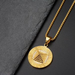 Détail macro du pendentif pyramide dorée avec pavé de cristaux et motif grec