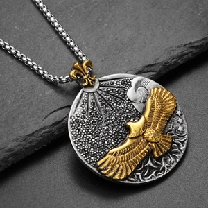 Détail macro du médaillon aigle en argent avec relief aigle doré et chaîne perlée