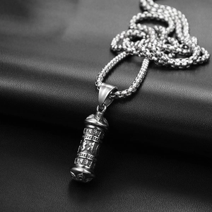 Vue rapprochée d'un pendentif cylindrique en acier titane avec symboles sanskrits gravés