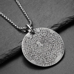 Détail macro du pendentif disque aigle en titane style industriel à texture pointillée
