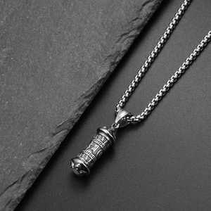 Vue macro d'un pendentif cylindrique en acier titane vintage avec symboles sanskrits