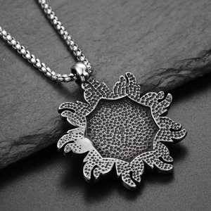 Détail macro du pendentif soleil argenté avec surface texturée sur chaîne vénitienne
