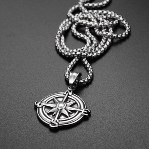 Dettaglio della collana con ciondolo a bussola argentata su sfondo nero smerigliato