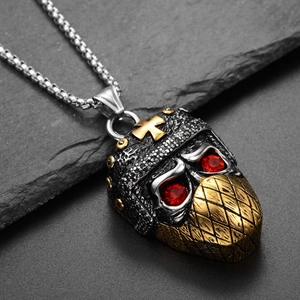 Macro shot of punk skull ninja pendant with red crystal eyes and golden cross on rock