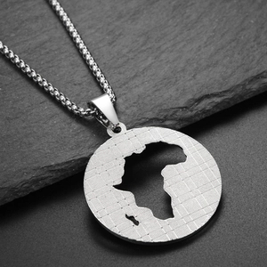 Macro shot of silver hollow African map pendant with textured grid on dark stone base