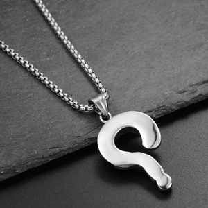 Vue macro d'un pendentif point d'interrogation en acier inoxydable poli sur chaîne à billes