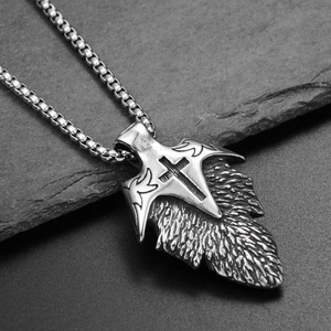 Makroaufnahme von Vintage-Edelstahl-Federanhänger mit Kreuz und Flügeldetails