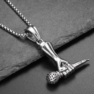 Macro shot of a hand clutching a microphone pendant on a silver box chain necklace