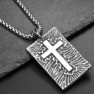 Macro shot of Gothic rectangular pendant with embossed cross on a textured steel chain