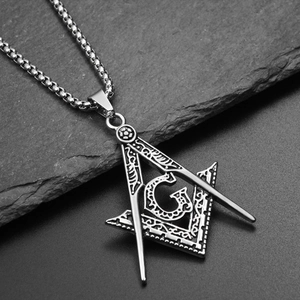 Macro shot of stainless steel Freemason pendant with compass and square on stone