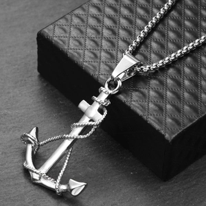 Detailed close-up of a silver anchor pendant with rope detail on a black textured box