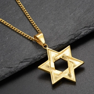 Gros plan d'un collier pendentif hexagramme doré avec une finition polie sur fond d'ardoise