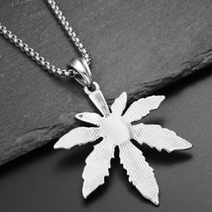 Macro shot of maple leaf pendant in titanium steel with detailed textures on rock base